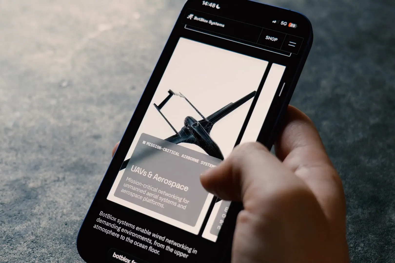 Hand holding a smartphone on the BotBlox Systems website, UAVs and aerospace page, designed by Mugdha Studios
