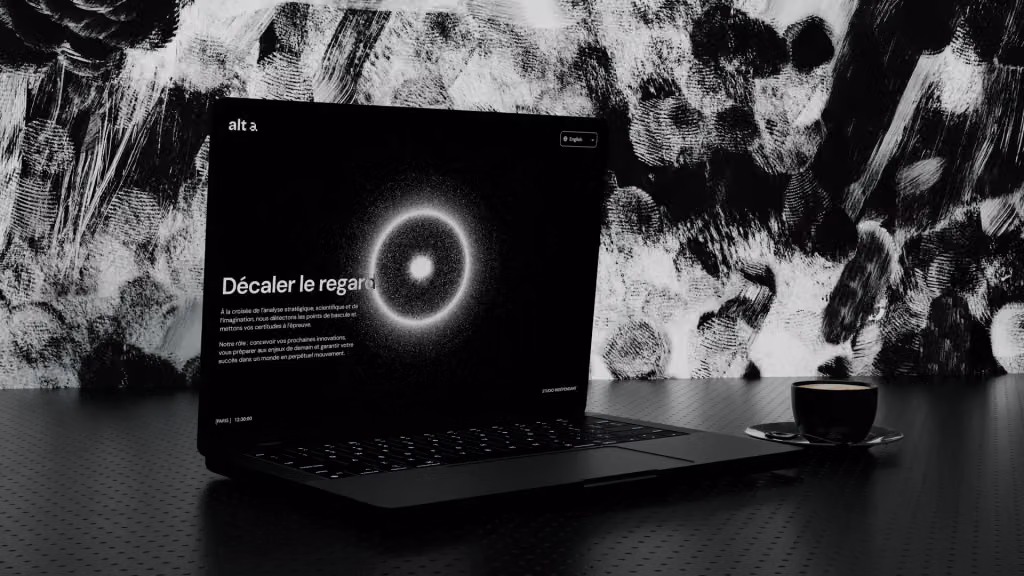 The Alt-a website open on a laptop, its headline “Décaler le regard” beside a glowing ring of light