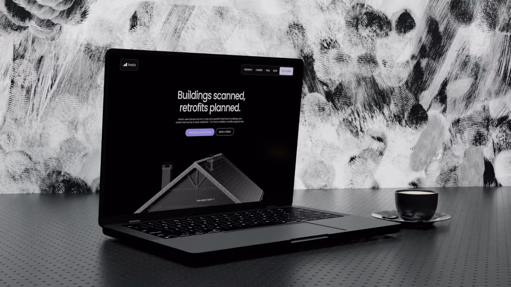 The Kestrix website open on a laptop: “Buildings scanned, retrofits planned.” above a 3D cutaway of a house roof
